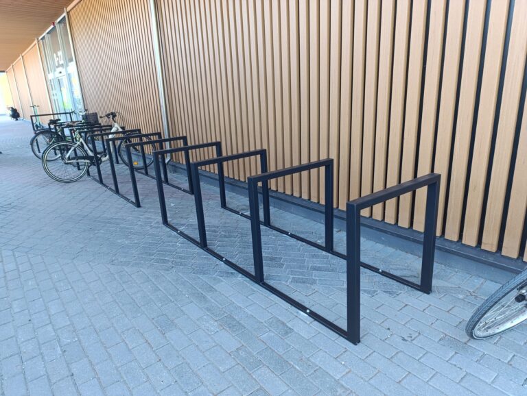 Divi tipveida velostatīvi, vienā novietoti velosipēdi un otrs tukšs