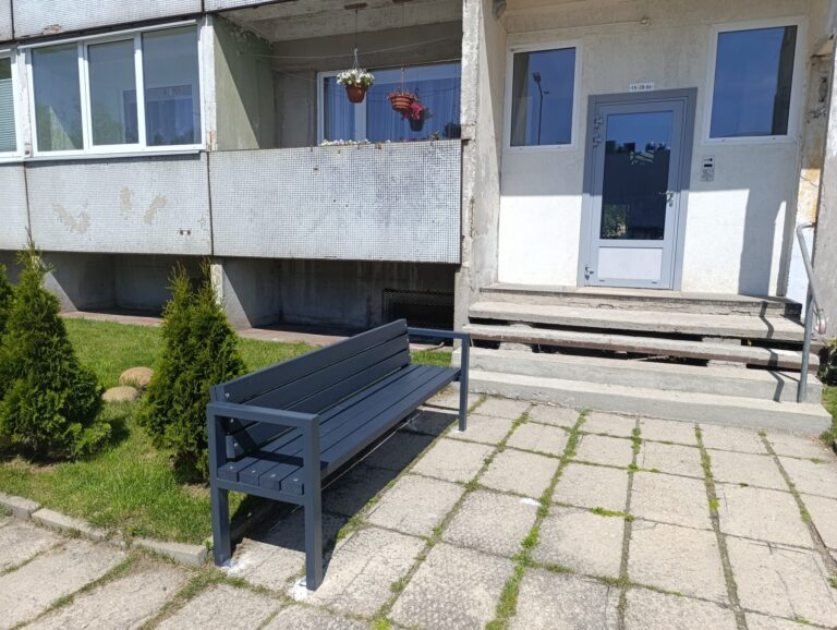 Pelēks sols ar atzveltni uzstādīts pie daudzdzīvokļu nama kāpņu telpu